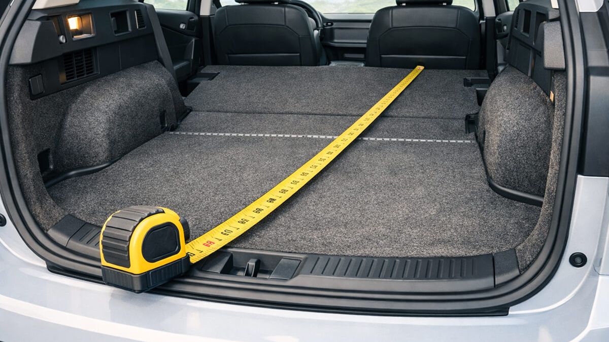 Tape measure inside a folded-seat trunk showing usable cargo length for long flat-pack boxes
