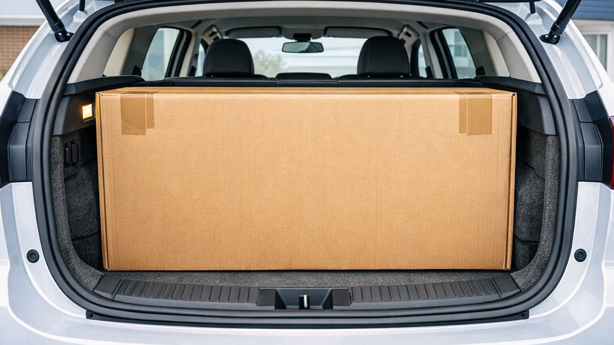 Large flat-pack box filling a car trunk opening to illustrate the limiting factor in a fit check