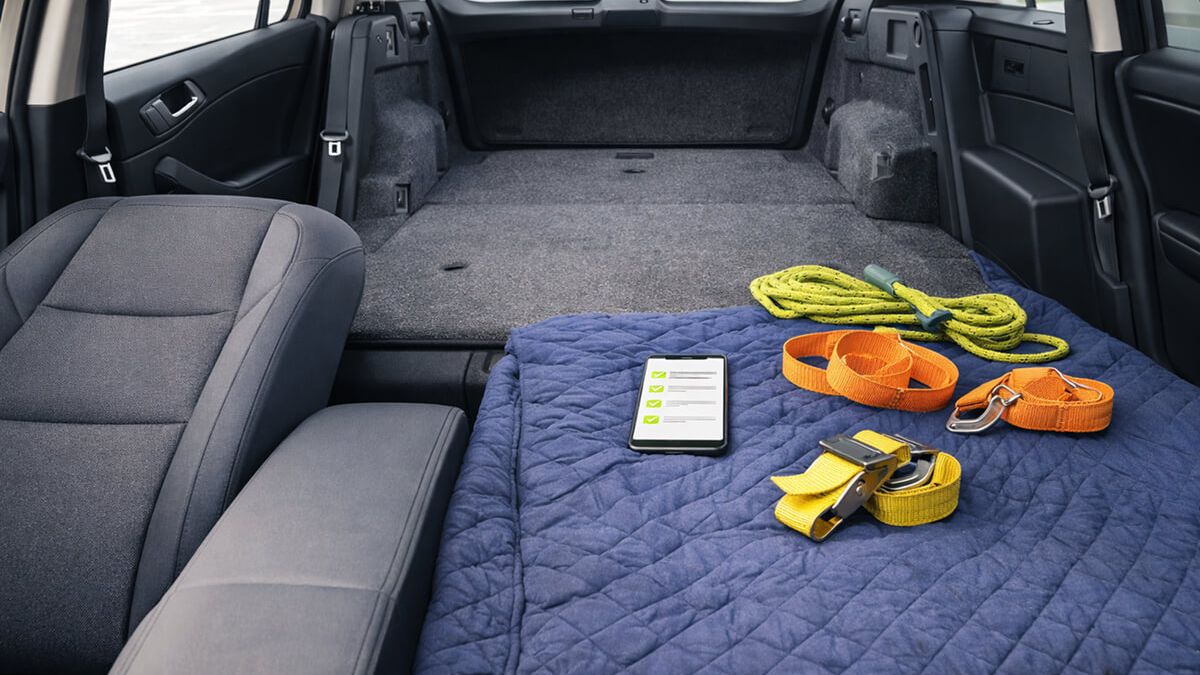 Folded rear seats, blanket, straps, and checklist phone ready inside a car for IKEA pickup day
